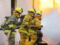 three firefighters with a hose putting out a fire