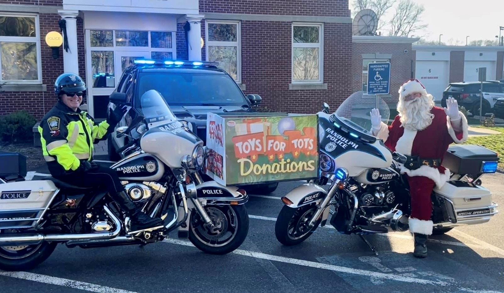 Randolph police on motorcycles holding a box for Toys for Tots with Santa in front of police station